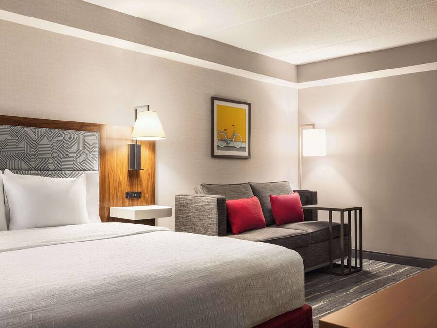 A hotel room with a large bed, a sofa, a small table, and a lamp.