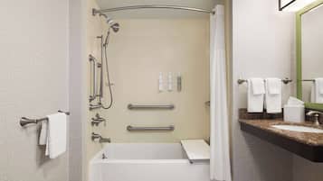 A modern bathroom with a bathtub, shower, and vanity with a sink and mirror.