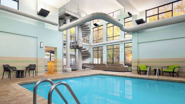 An indoor swimming pool with a spiral staircase, lounge chairs, and a tiled floor. - Hampton Inn by Hilton Shelton (Shelton)