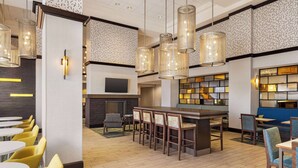 A modern hotel lobby with a bar area, seating arrangements, and decorative lighting. - Hampton Inn by Hilton Shelton (Shelton)