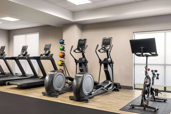 A gym with treadmills, elliptical machines, and a stationary bike.