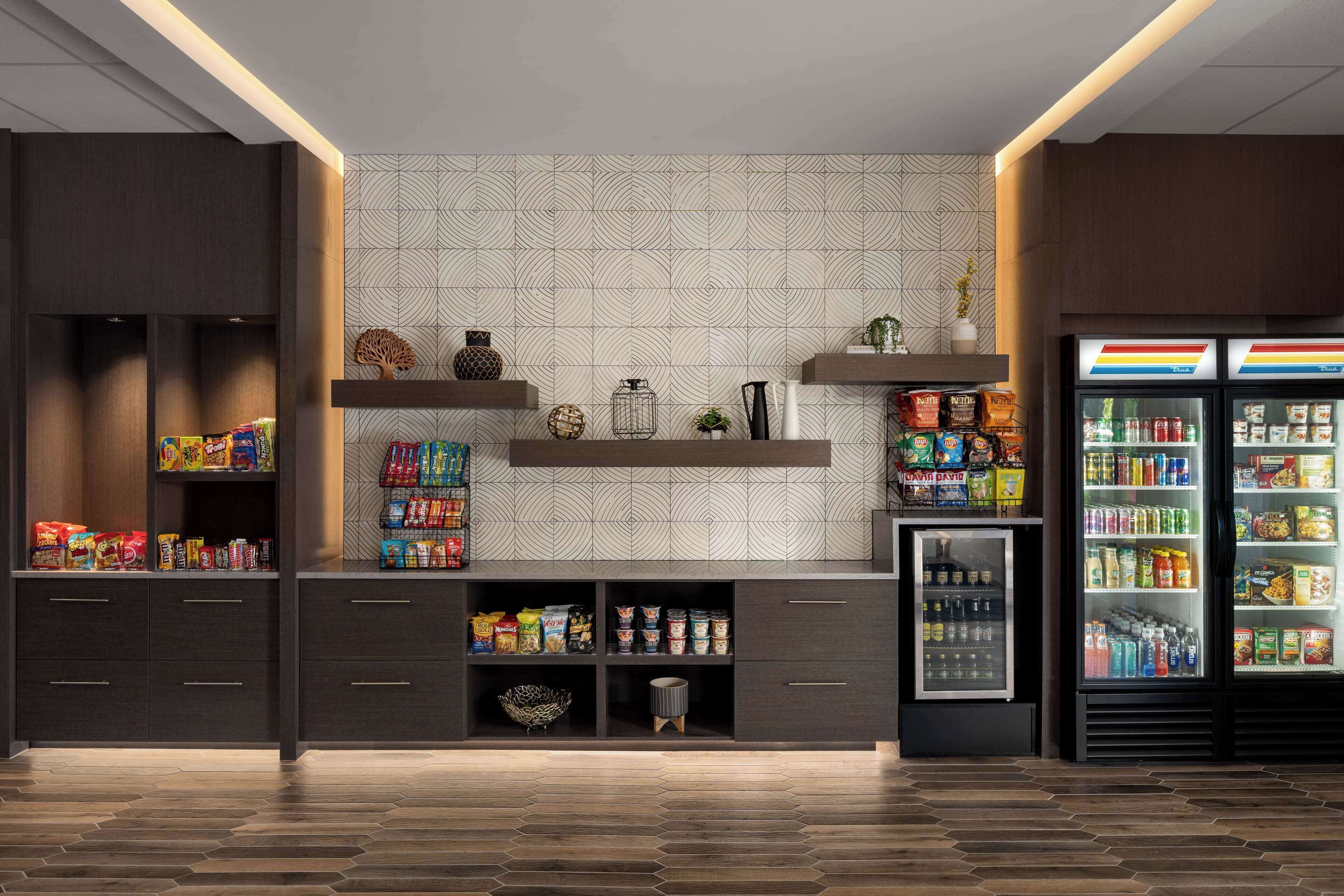 Una cocina moderna con armarios oscuros, un salpicadero decorativo y un refrigerador lleno de bebidas y aperitivos.