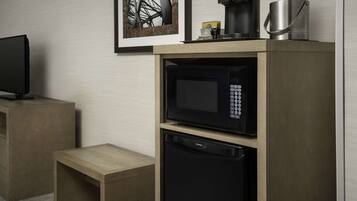 Una kitchenette compacta equipada con microondas, cafetera y refrigerador pequeño.