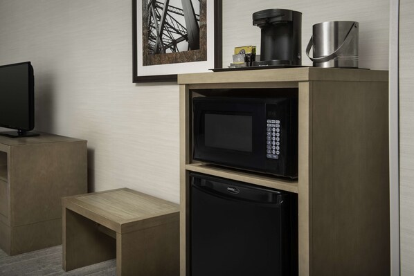 Una kitchenette compacta equipada con microondas, cafetera y refrigerador pequeño.