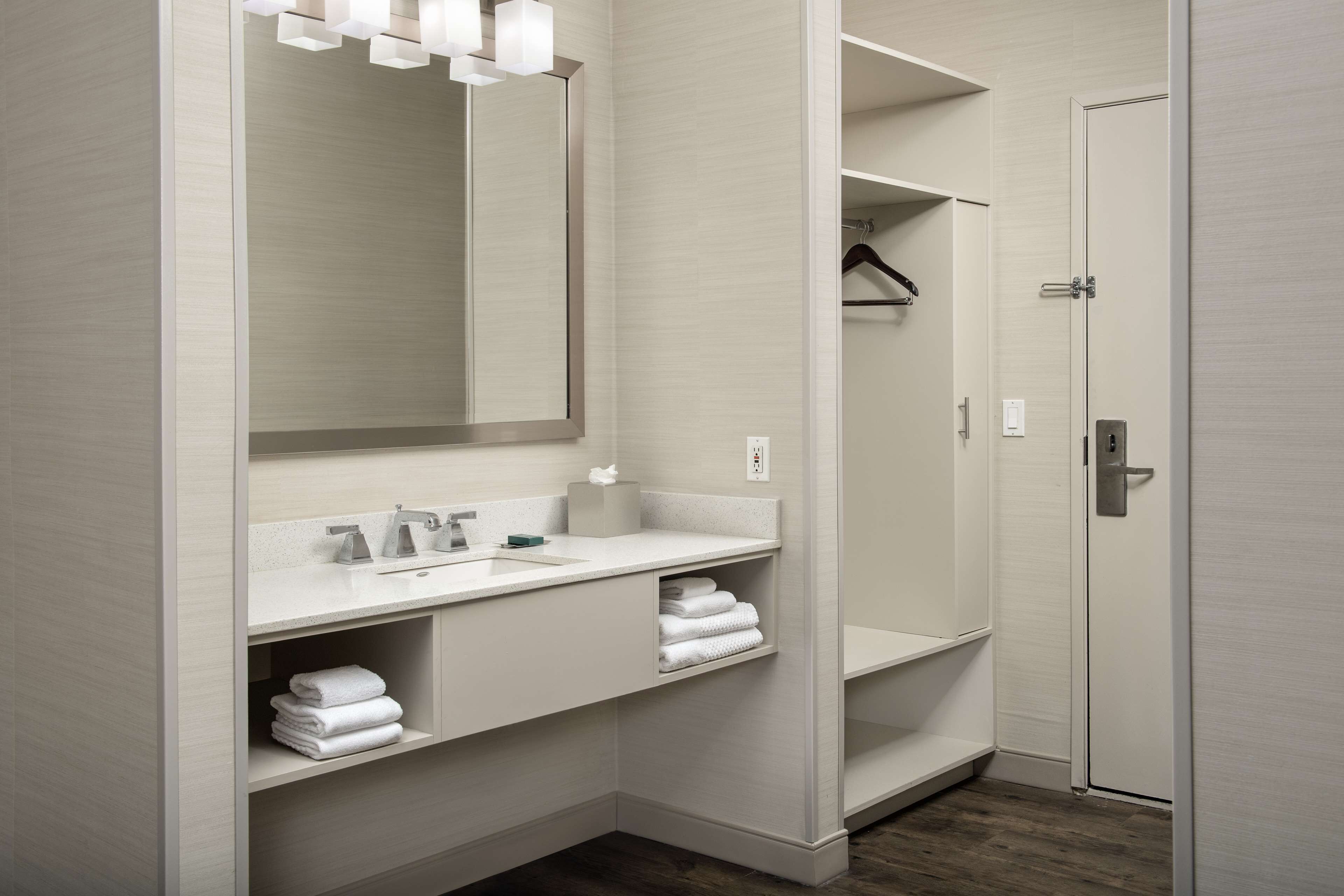 A modern bathroom with a large mirror, a sink, and a shower area.