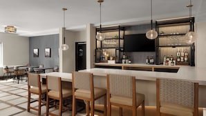 A modern kitchen with a bar area, wooden chairs, and a dining table.