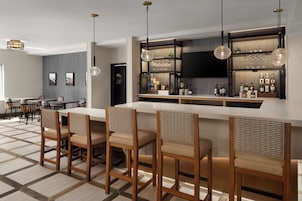 A modern kitchen with a bar area, wooden chairs, and a dining table.