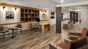 A modern lobby with a wooden reception desk, seating area, and a fireplace.