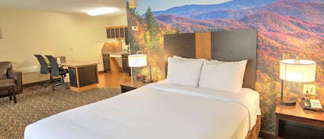 Habitación de hotel con una cama grande, un escritorio con silla, una lámpara de escritorio, un teléfono y un televisor montado en la pared.
