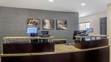 A reception area with a dark wood reception desk, two Dell computers, and a welcome sign.