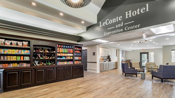 A hotel lobby with a reception desk, seating area, and a Convention Center sign. - LeConte Hotel & Convention Center, an Ascend Collection Hotel (Pigeon Forge)