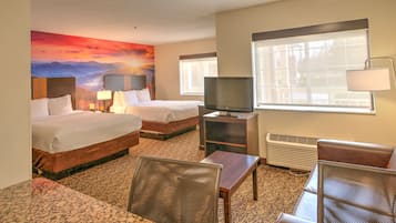 Una habitación de hotel con dos camas, un televisor, un escritorio y una silla.