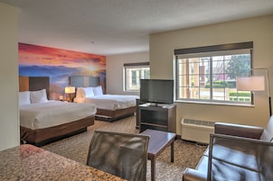 A hotel room with two beds, a television, a desk, and a chair.