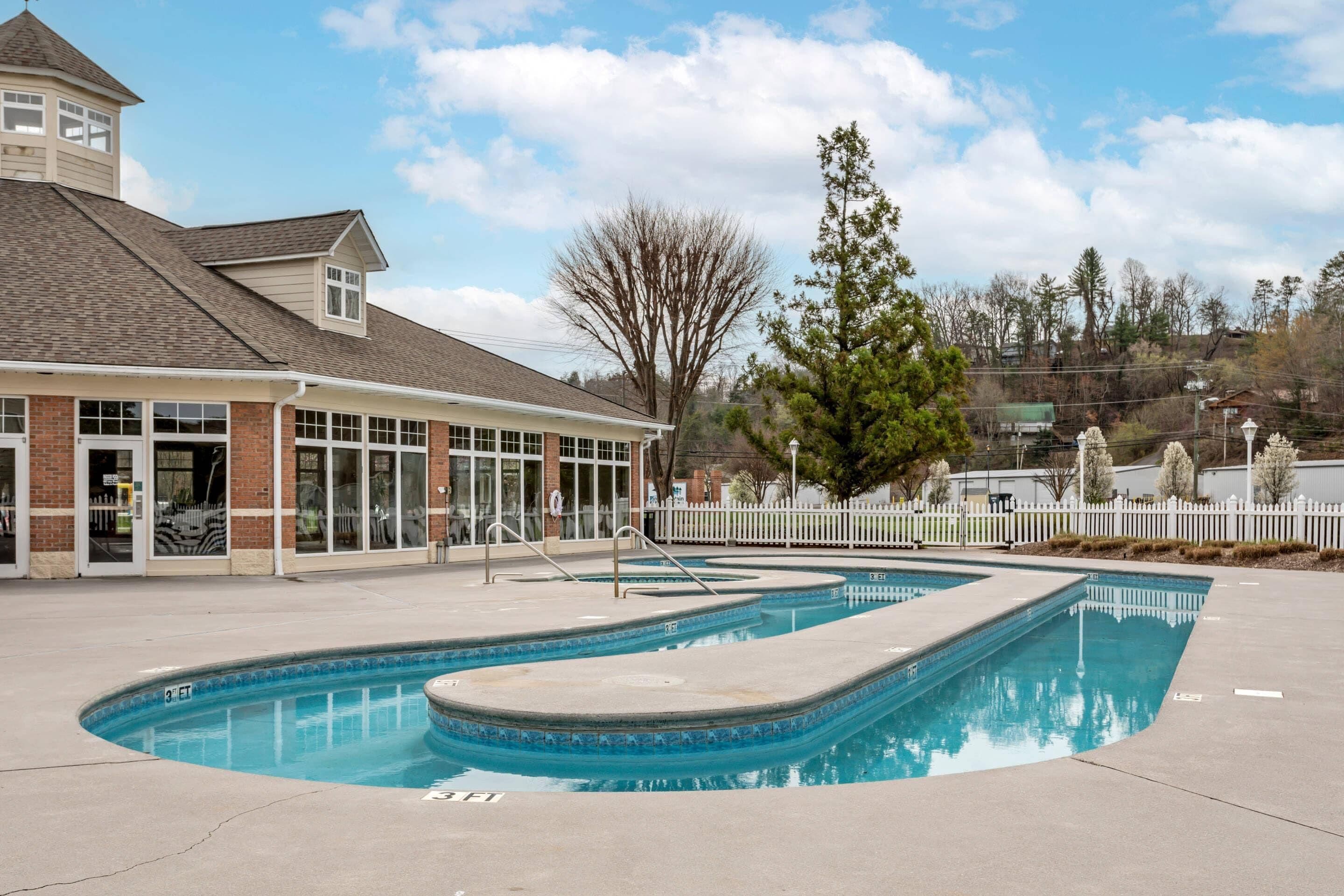 A swimming pool area with a building that has large windows and a tower-like structure.
