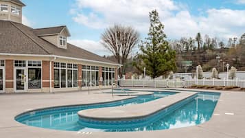 A swimming pool area with a building that has large windows and a tower-like structure.