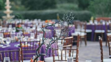 A dining area with tables set for a meal, featuring purple tablecloths and wooden chairs.