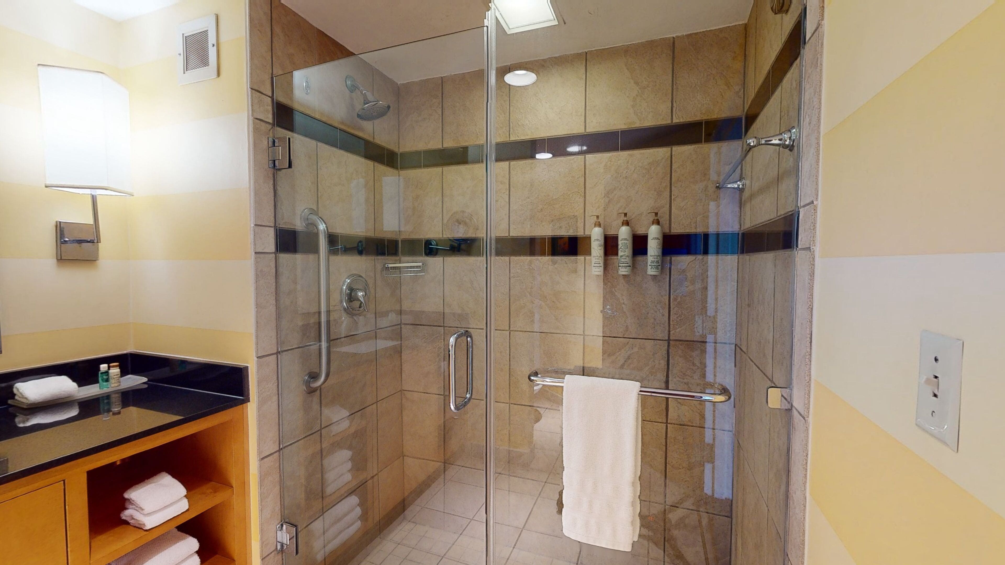 A modern bathroom with a glass-enclosed shower, a vanity with a black countertop, and a towel rack.