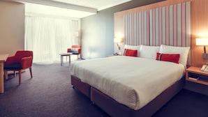 Une chambre d’hôtel avec un grand lit, un bureau, une chaise et une table de chevet avec une lampe.