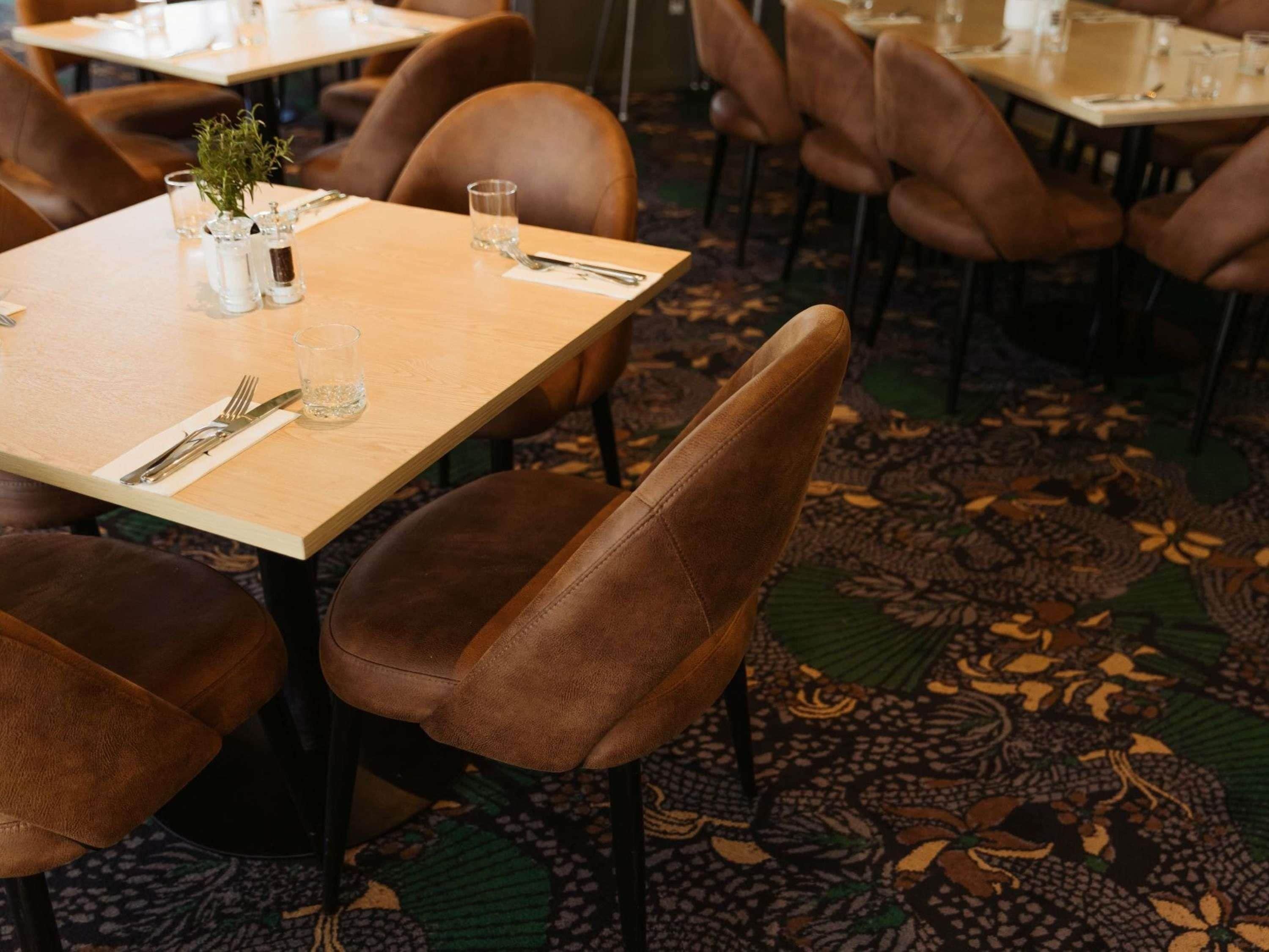 A dining area with tables set for two, equipped with cutlery and glasses.