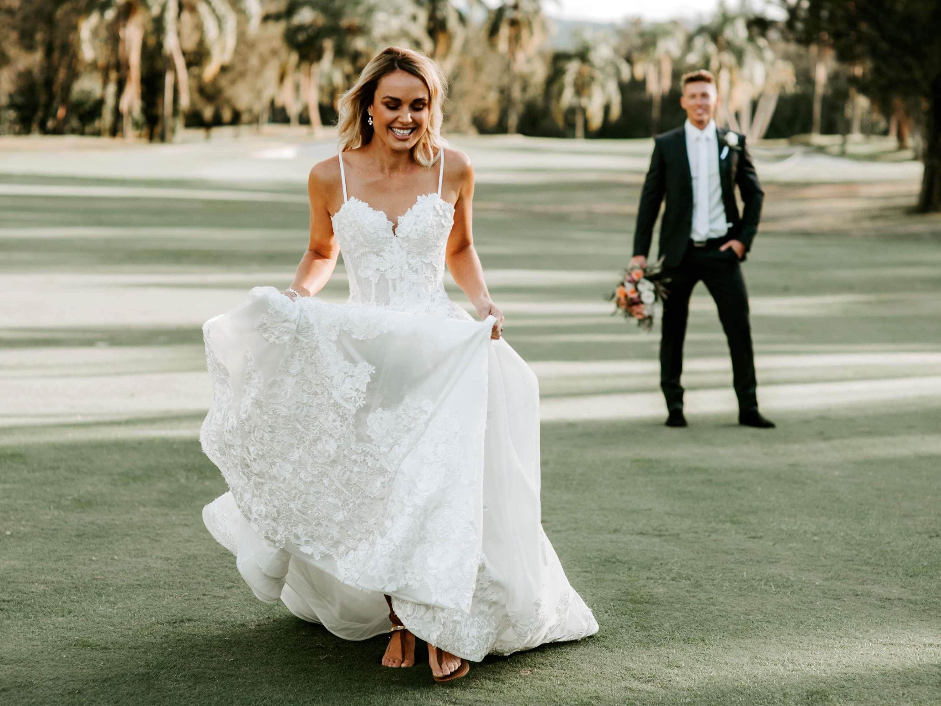 A wedding scene on a golf course with a bride in a white dress and groom in a suit.