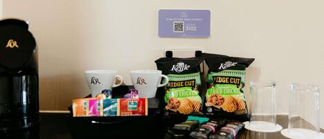 A coffee station with two white cups, a kettle, a tray with snacks, and a QR code for room 3102.