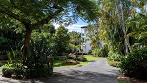A residential area with a paved driveway leading to a white building with a balcony. - Mercure Gold Coast Resort (Carrara)