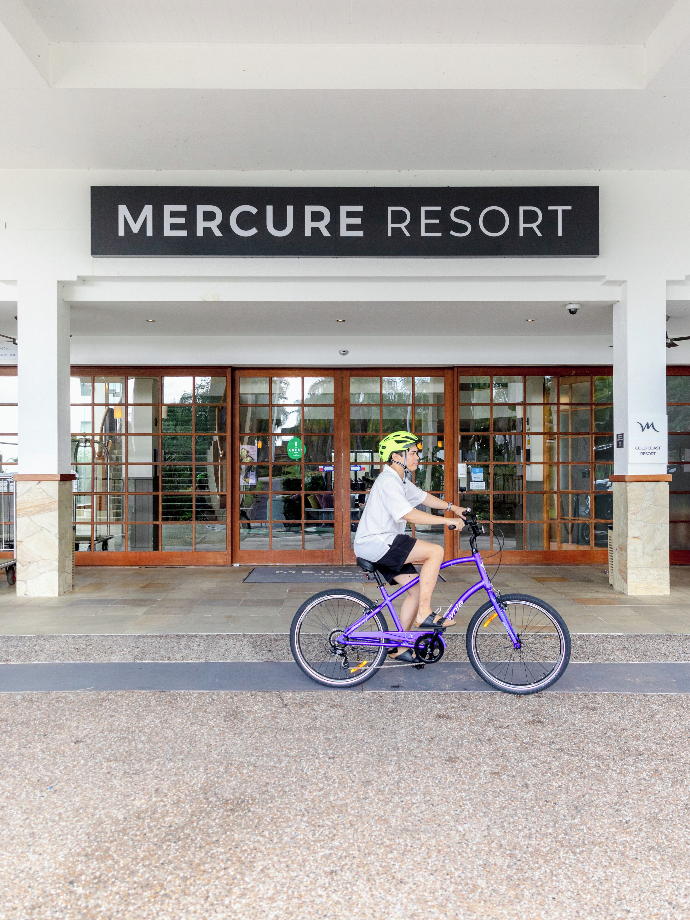 Una persona montando en bicicleta frente a un edificio con la leyenda 'Mercure Resort'.