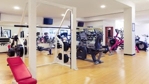 Une salle de sport équipée de divers appareils d’exercice, notamment des tapis de course, des vélos d’appartement et des appareils de musculation.