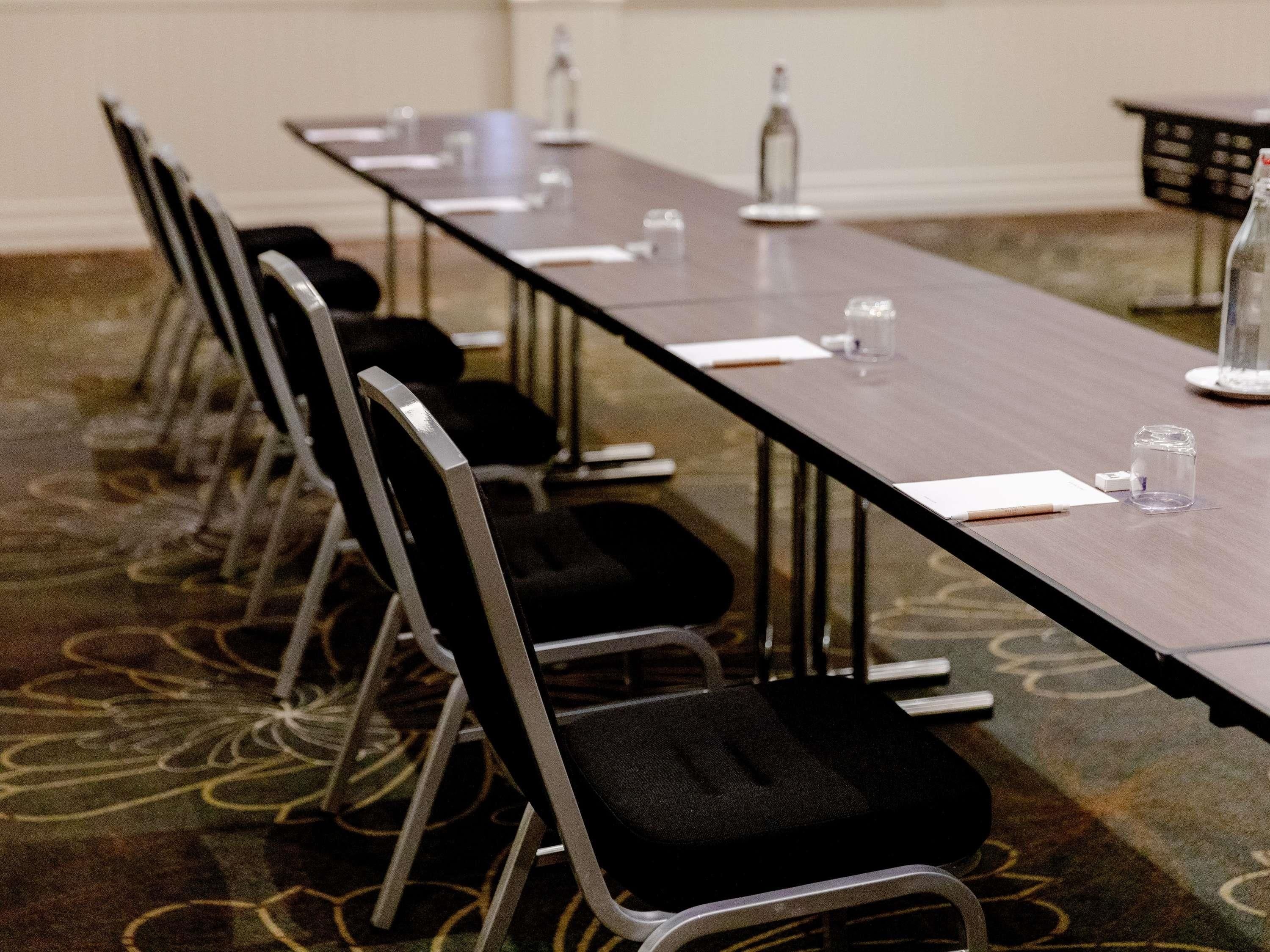 A conference room with a long table, chairs, water bottles, and glasses.