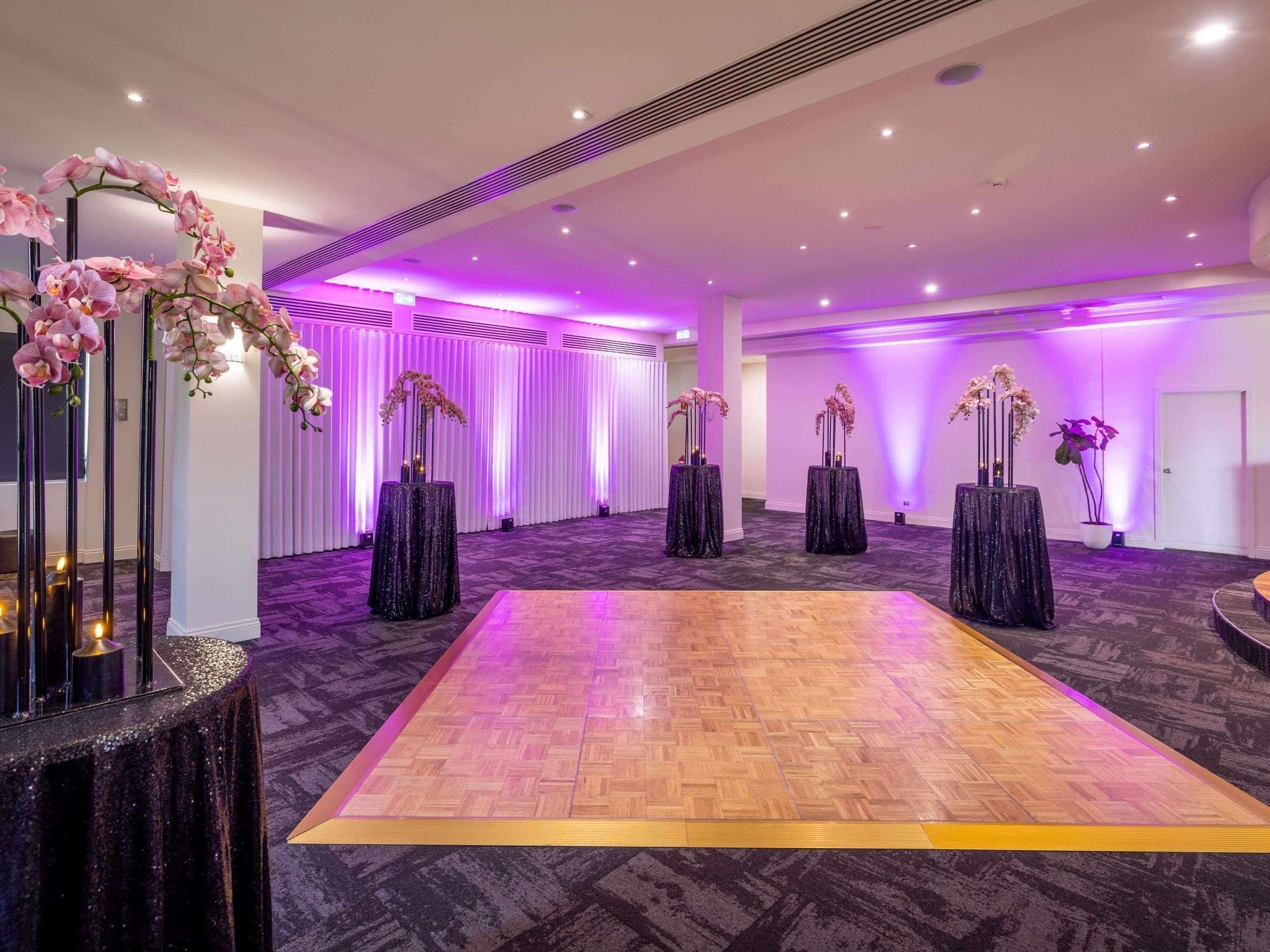 Un espacio interior amplio con pista de baile, arreglos florales decorativos y un diseño de techo moderno.