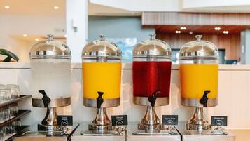 Un distributeur de boissons proposant de l’eau, du jus d’orange, du jus de pomme et du jus d’ananas.