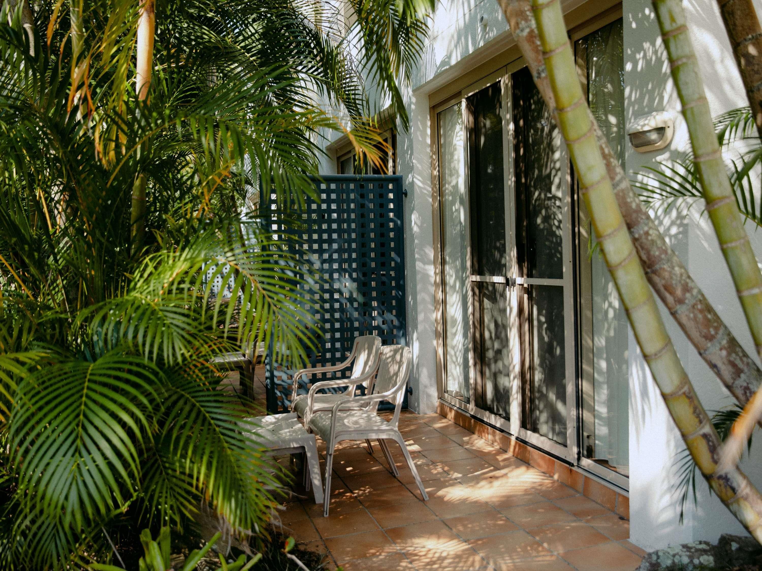 A patio area with a seating arrangement, a blue fence, and a large sliding glass door.