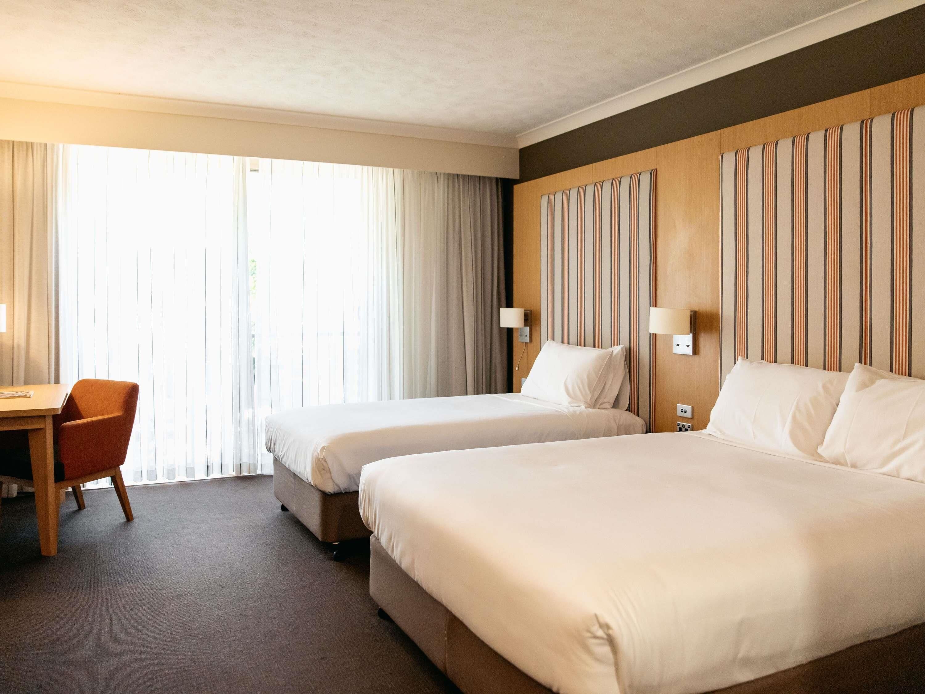 Habitación de hotel con dos camas, un escritorio y una silla.