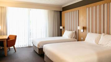 Habitación de hotel con dos camas, un escritorio y una silla.
