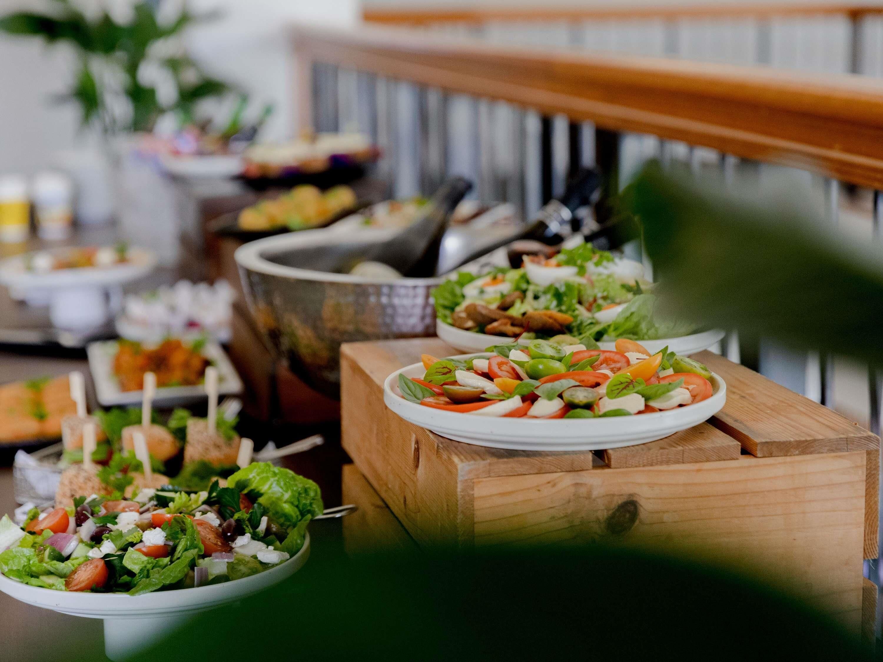 Uma mesa de buffet com diversos pratos, incluindo saladas e uma tigela de sopa.
