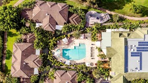 An aerial view of a resort with multiple buildings, a central swimming pool, and surrounding greenery. - Mercure Gold Coast Resort (Carrara)