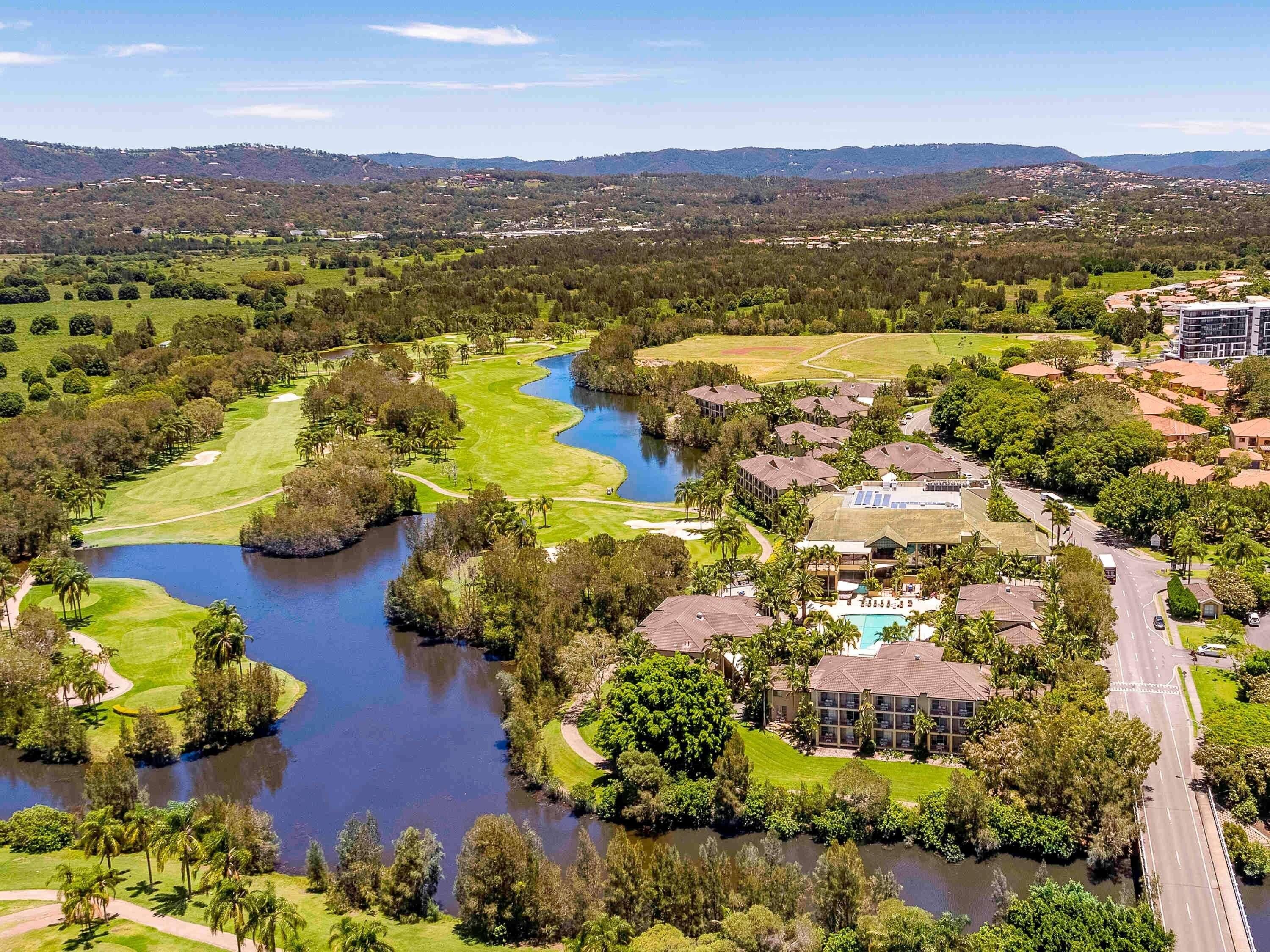 Un camp de golf amb un llac, envoltat d'edificis residencials i un hotel.