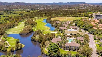 Un camp de golf amb un llac, envoltat d'edificis residencials i un hotel.