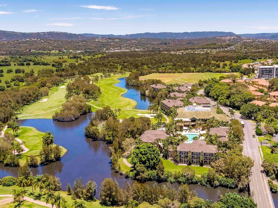 Un parcours de golf avec un lac, entouré de bâtiments résidentiels et d’un hôtel.