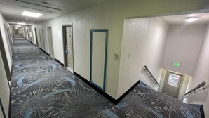 A hotel hallway with a patterned carpet, doors, and an elevator. - Days Inn by Wyndham Holladay (Holladay)