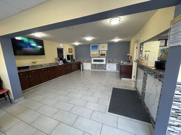 A spacious kitchen with a large island, recessed ceiling lights, and a tiled floor.