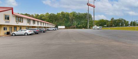 A motel with multiple rooms, a parking lot, and a restaurant sign in the background.