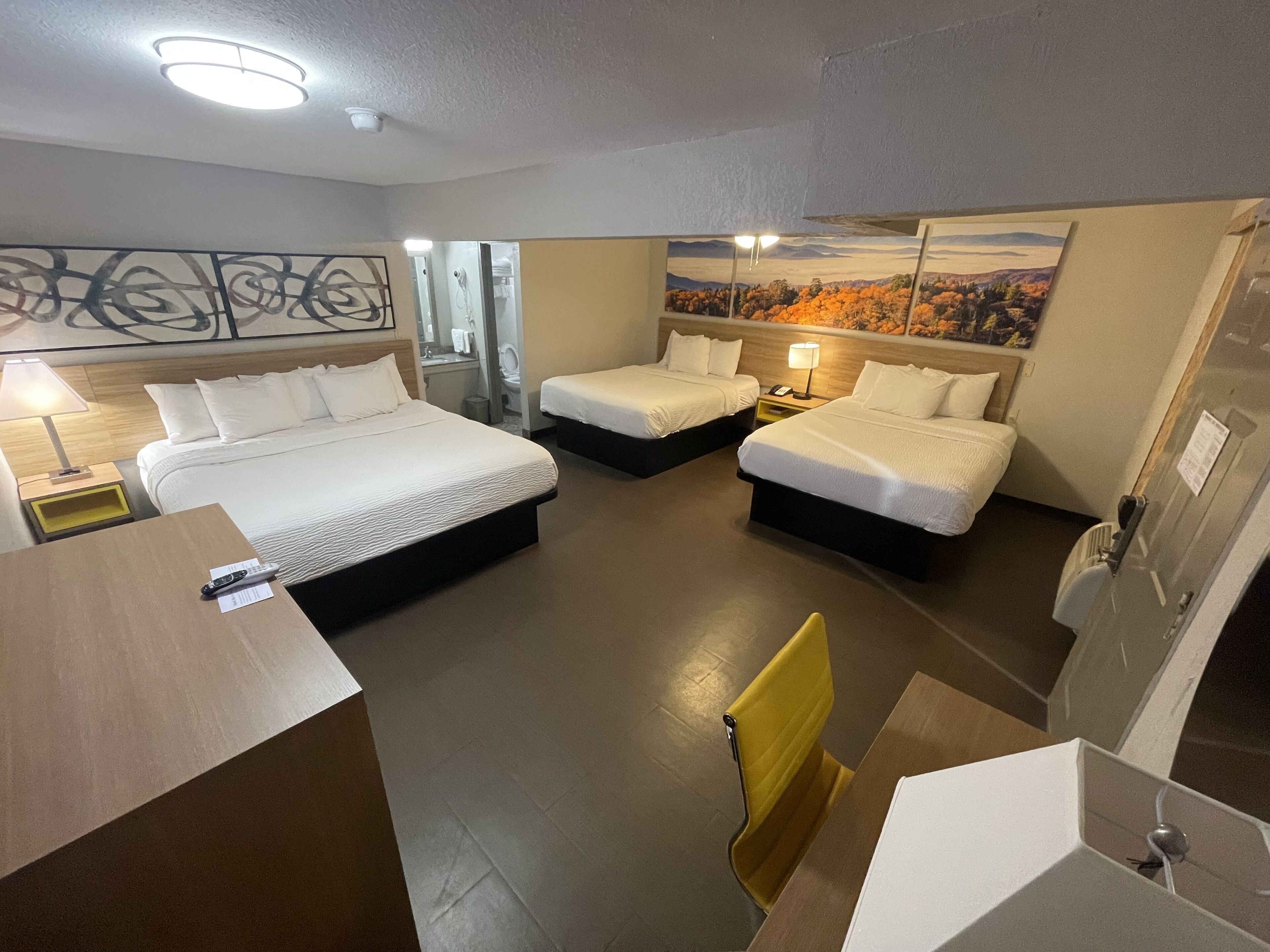 Une chambre d’hôtel avec deux lits, une salle de bain, un bureau et une chaise.