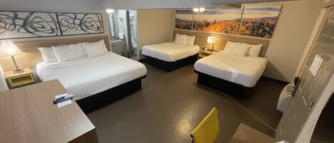 A hotel room with two beds, a bathroom, a desk, and a chair.