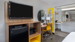 A hotel room with a flat-screen TV, a desk with a chair, a microwave, and a mini-fridge. - Days Inn by Wyndham Holladay (Holladay)