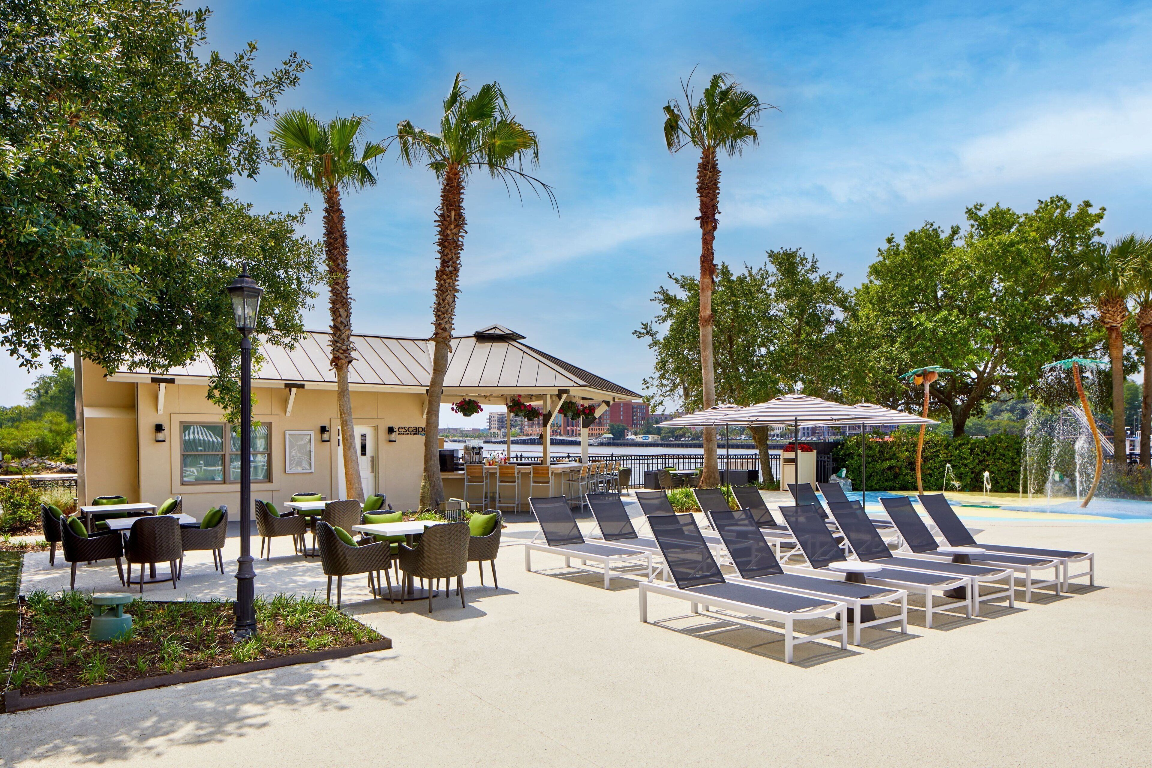 A resort with outdoor seating, palm trees, and a pool area.