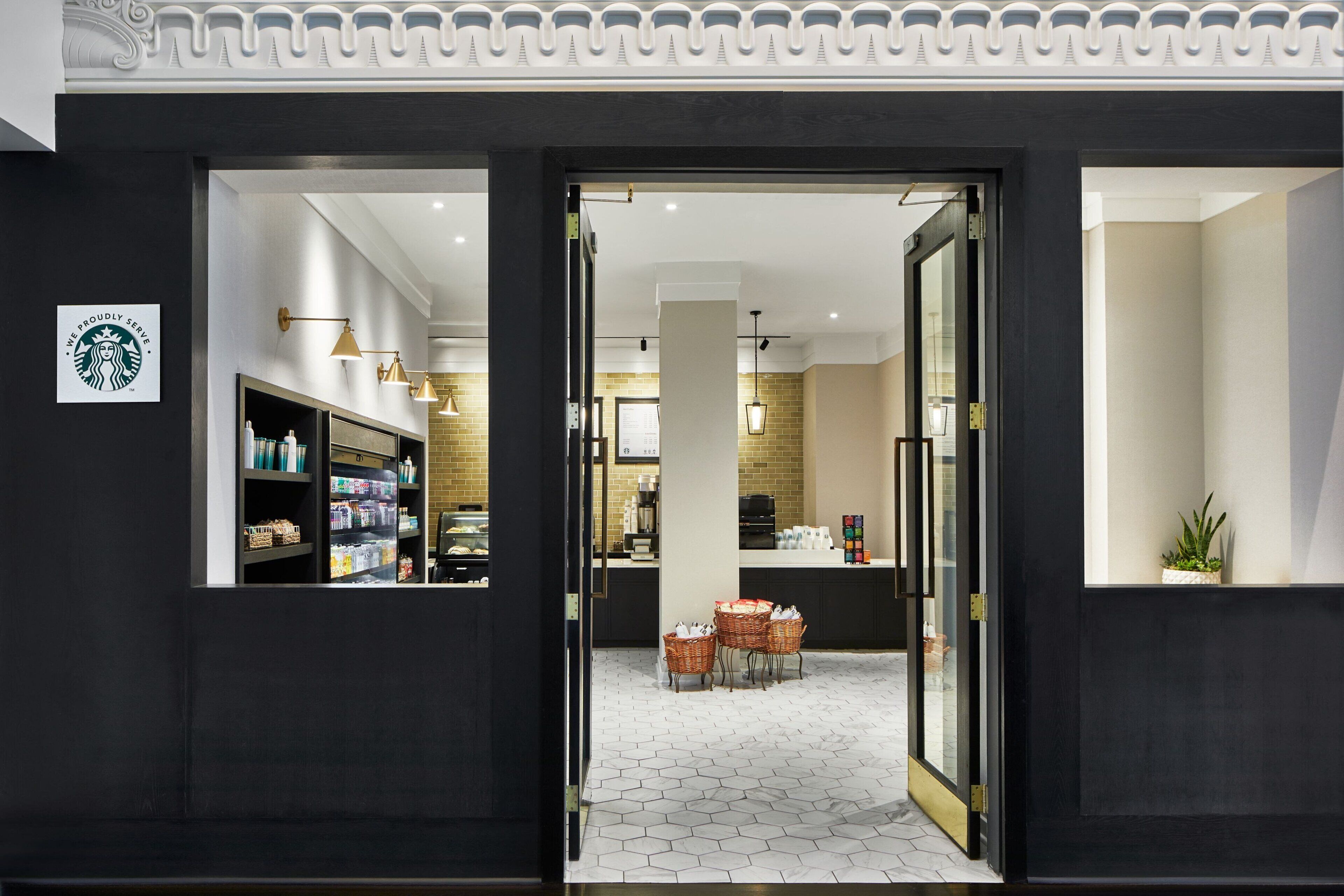 Entrada de Starbucks con un interior moderno, que incluye una zona de estar con cestas y suelo de baldosas.