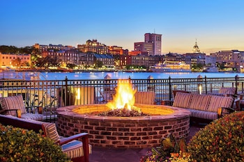 A high-rise hotel with a pool, located near a river with a bridge in the background. at The Westin Savannah Harbor Golf Resort & Spa