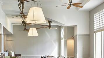 A spacious dining area with high ceilings, ornate ceiling fans, and large windows allowing natural light.