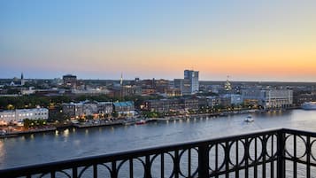 A cityscape at dusk with a river, buildings, and a boat.